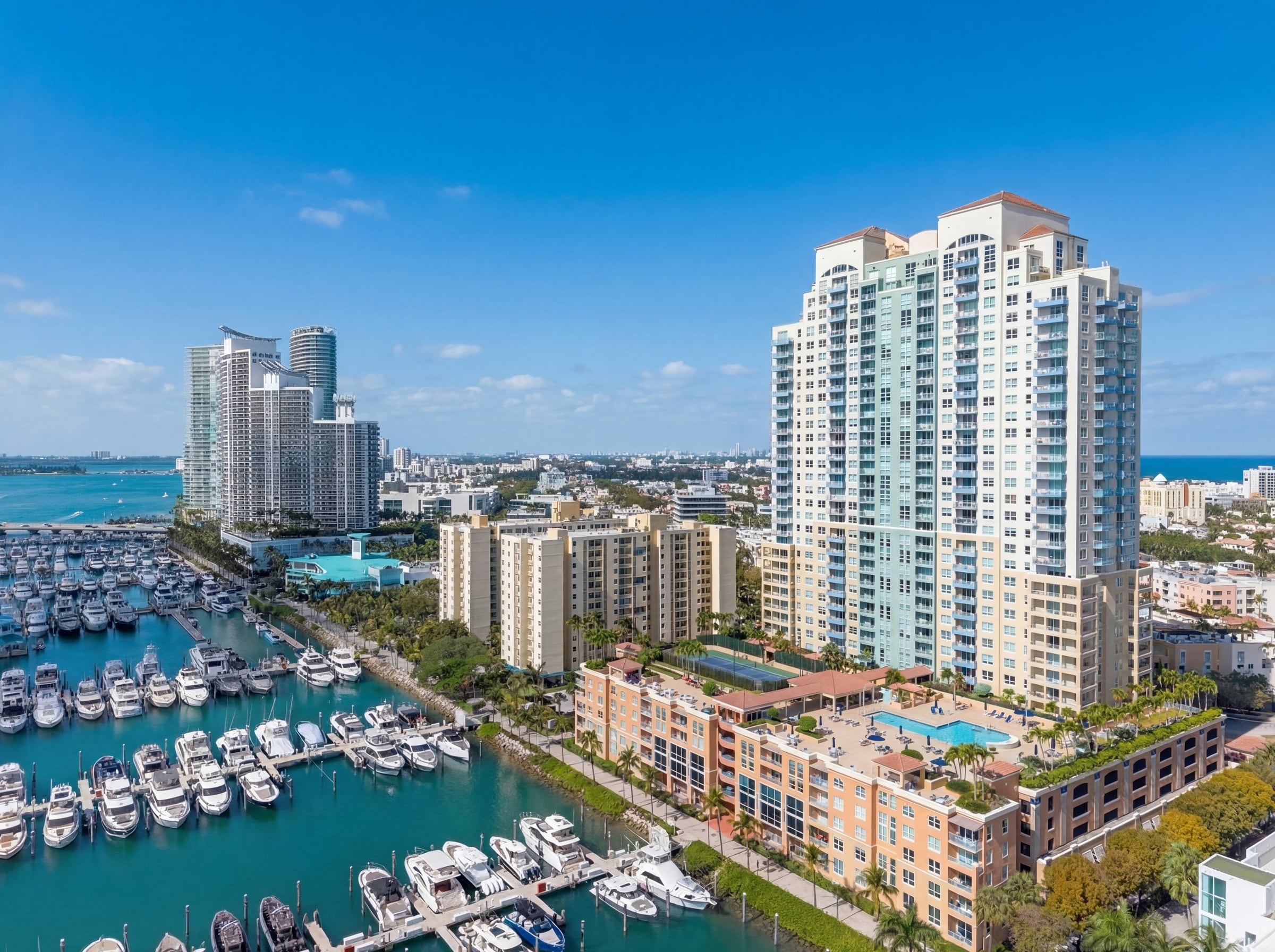 Daylight aerial of a coastal residential tower and a densely lined private marina