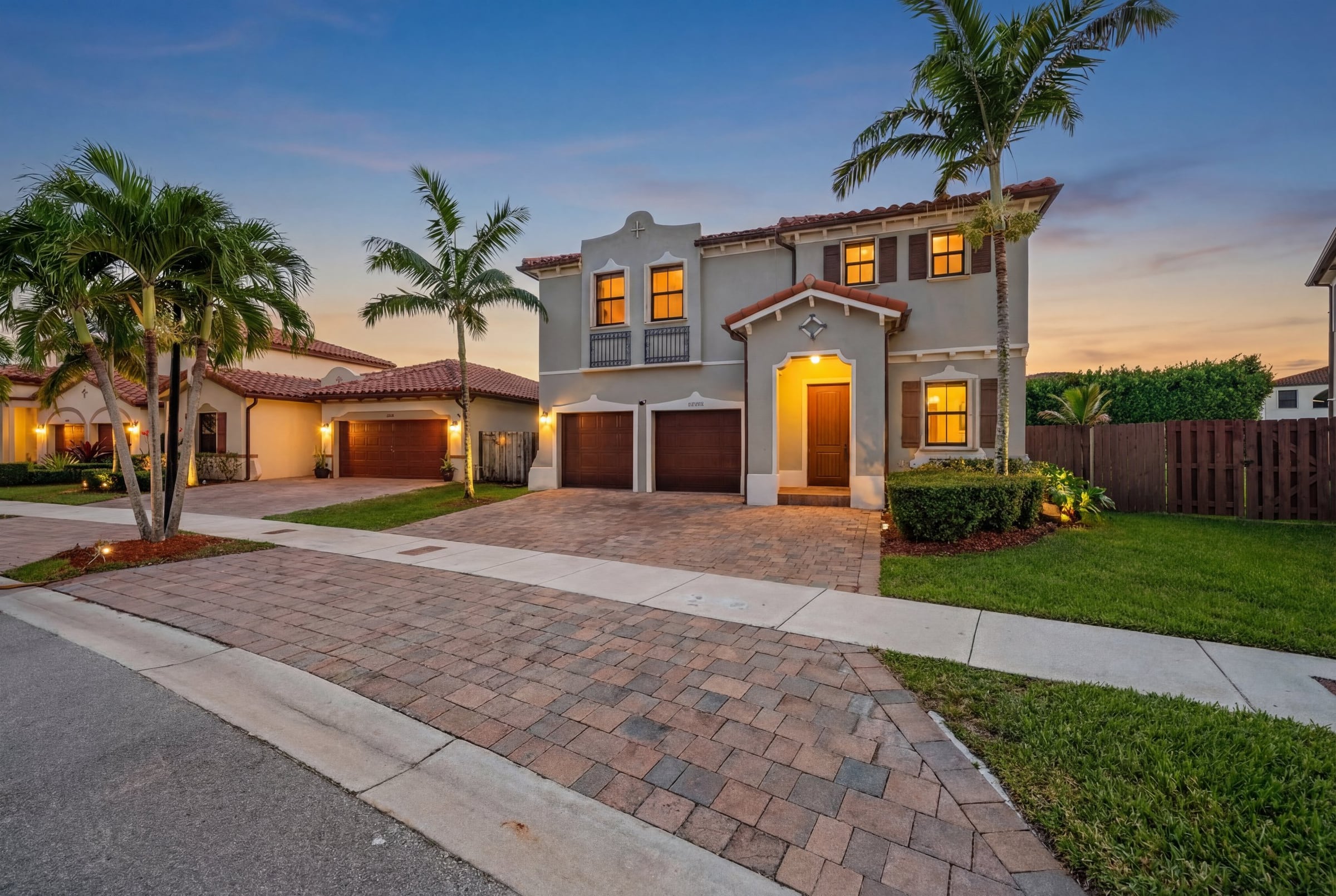 Two-story contemporary home glowing against a soft South Florida twilight sky