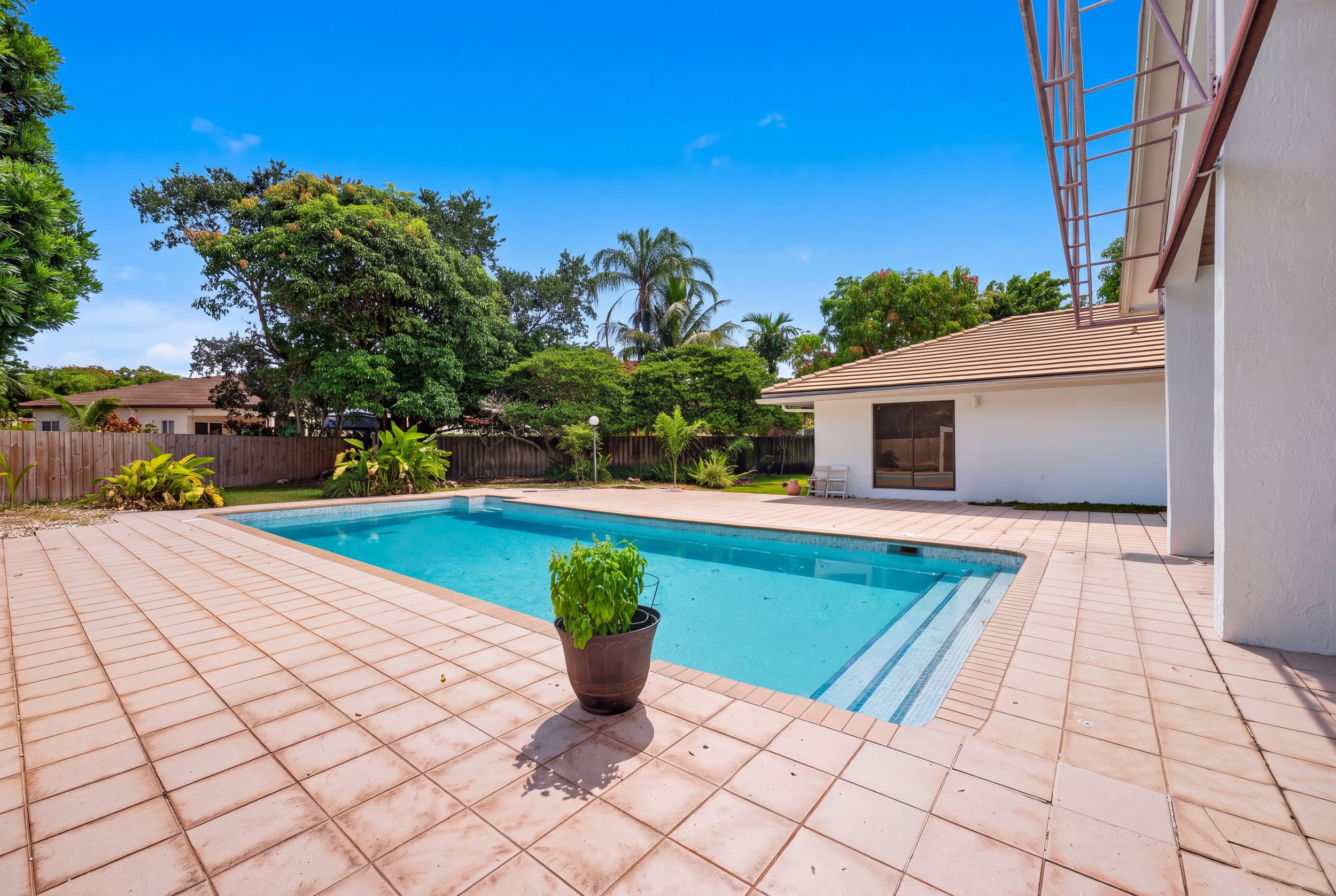 Daylight view of a Pinecrest pool patio and tropical backyard