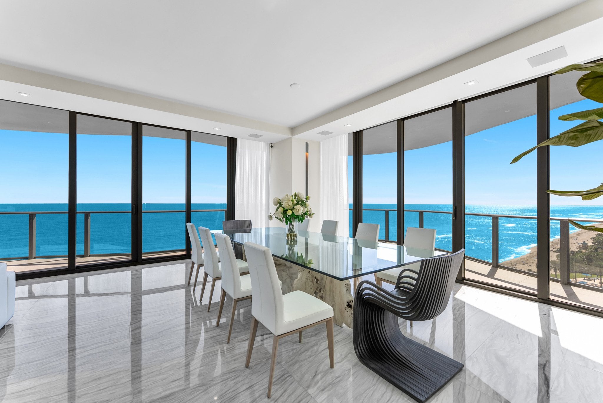 Bright oceanfront living room surrounded by glass walls and uninterrupted blue water